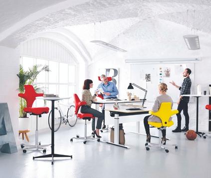 Designers in a brainstorming session at a conference table that can be converted into a standing desk