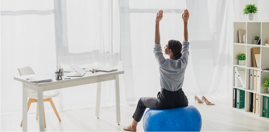 Photo of a young happy businesswoman doing fitness exercise on pilates ball in the office