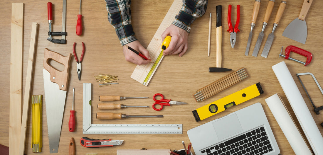 Photo of the hand of a man taking a measurement of a wooden plank and carpentry tools around 